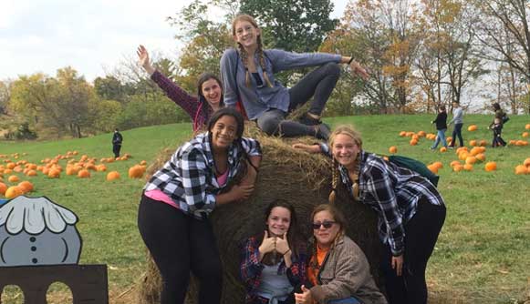 Students sitting on a hay bale